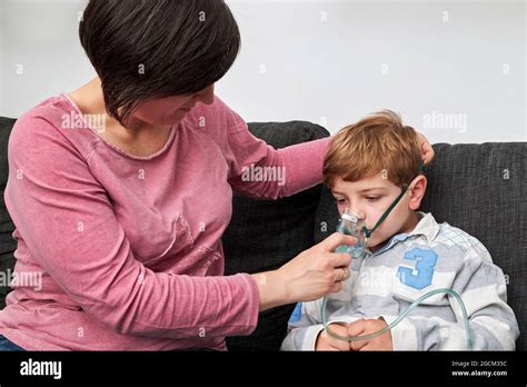 Content Mother Putting On Oxygen Mask On Face Of Son For Inhalation