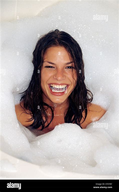 Female With Long Wet Brunette Hair In Bath With Bubble Bath Round Back