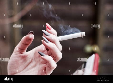 Woman Smoking Cigarette Outdoor And Holding In Hand With Grey And Pink