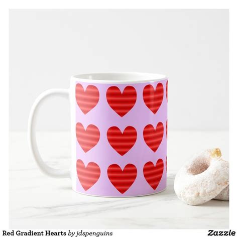 A Pink Coffee Mug With Red Hearts On It Next To A Donut