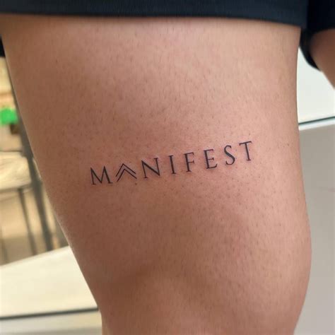 Tattoo Of The Word Manifest Located On The Thigh