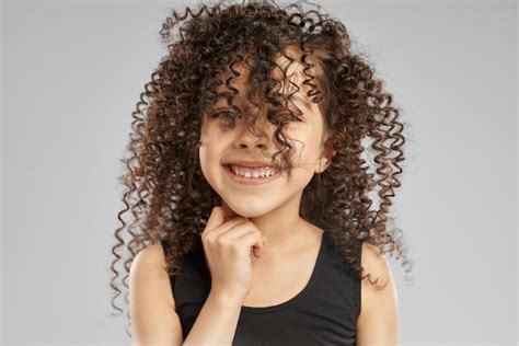 Petite Fille Souriante Aux Cheveux Bouclés Sur Le Visage Photo Gratuite