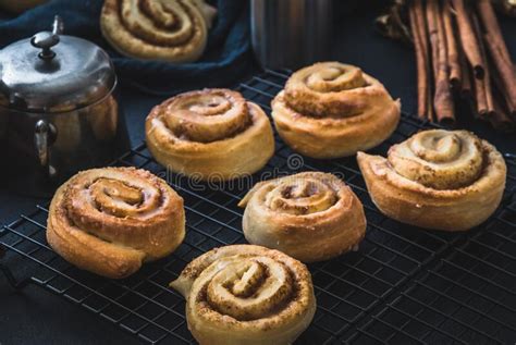 Homemade Cinnamon Rolls On A Cooling Rack With Cinnamon Sticks And