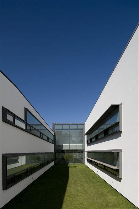 Two White Buildings With Black Windows And Grass