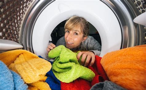 Woman Reaching Inside A Washing Machine Or Dryer At Laundry Stock Photo