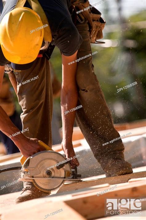 Carpenter Using A Circular Saw At A Construction Site Stock Photo