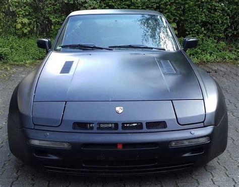 The Front End Of A Sports Car Parked On A Cobblestone Road With Trees