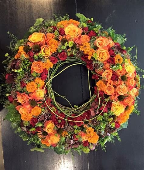 An Orange And Yellow Wreath With Greenery Around It