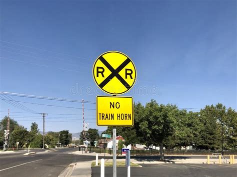 A Railroad Crossing Sign In Front Of Train Tracks Editorial Image