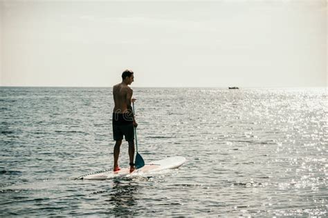 Side View Foto Of A Man Swiming And Relaxing On The Sup Board Sportive