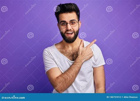 Cheerful Happy Bearded Man Indicates Happily At Somewhere Stock Photo