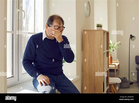 Desperate Mature Man Sitting Alone On A Windowsill And Crying Over Life