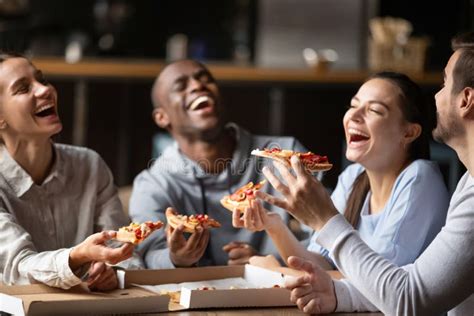 Diverse Friends Eating Pizza And Having Fun Together In Cafe Stock