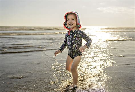 Menina Adorável 2 Anos Alegremente Na Praia No Pôr Do Sol De Férias