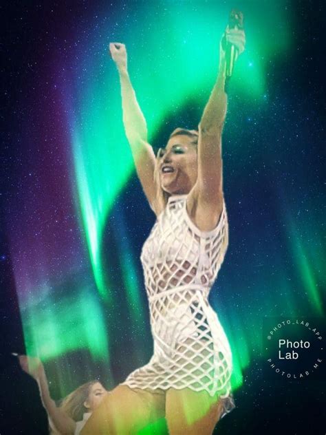 A Woman Is Dancing In Front Of The Aurora Lights With Her Arms Up And