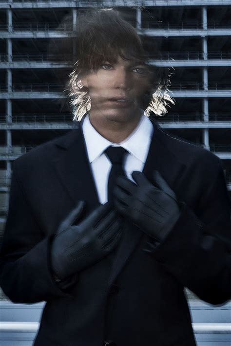 A Man In A Suit And Tie Wearing Black Gloves