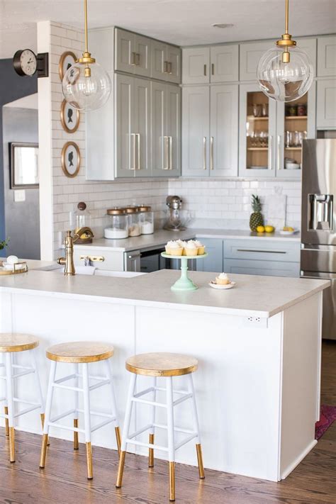 A Kitchen With Three Stools In Front Of The Island And Two Lights