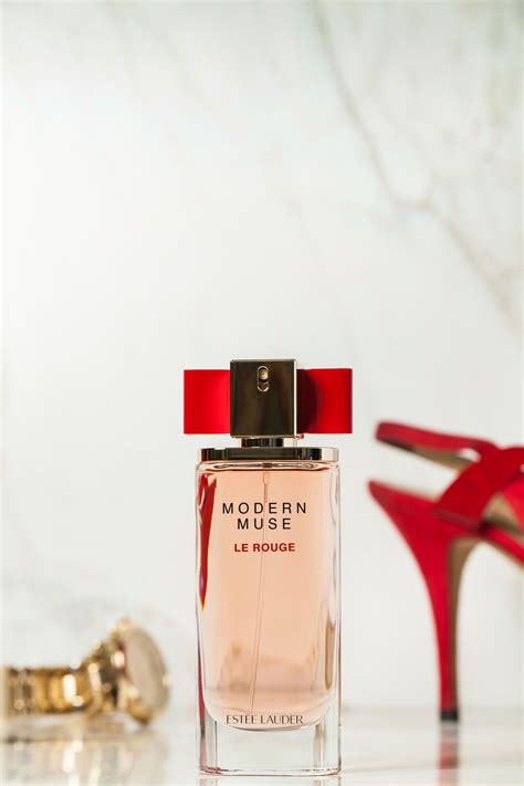 A Bottle Of Perfume Sitting On Top Of A Table Next To High Heeled Shoes