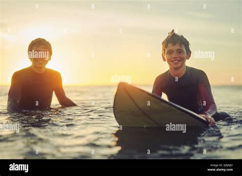 Feeling At Home On The Water Portrait Of Two Young Brothers Sitting On Their Surfboards In The