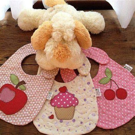 A Stuffed Animal Sitting On Top Of Three Bibs With Cupcakes And Cherries