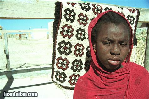 A Woman Wearing A Red Scarf Standing In Front Of A Quilt On The Ground