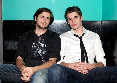 Two Men Sitting Next To Each Other In Front Of A Blue And Green Wall