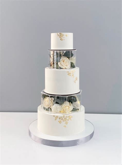 A Three Tiered White Cake With Gold Flowers On The Top And Bottom