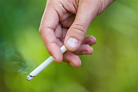 Premium Photo Man S Hand Holding A Lit Cigarette