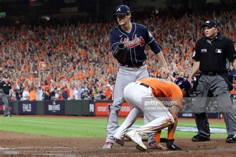 the baseball player is trying to slide into home plate as an umpire looks on from behind him