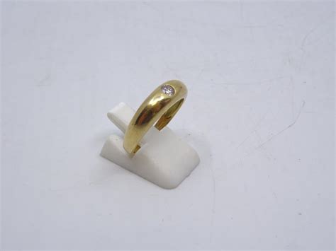 Une bague demi jonc en or jaune 750 ornée en serti clos d un diamant