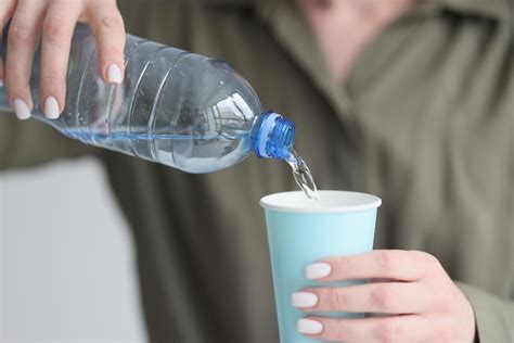 La Mujer Vierte Agua Fresca En Un Vaso De Papel De Una Botella De