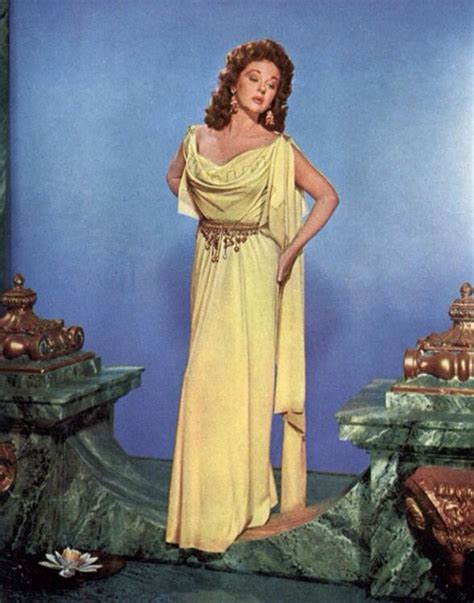 A Woman In A Yellow Dress Standing On A Stage With Her Hands On Her Hips