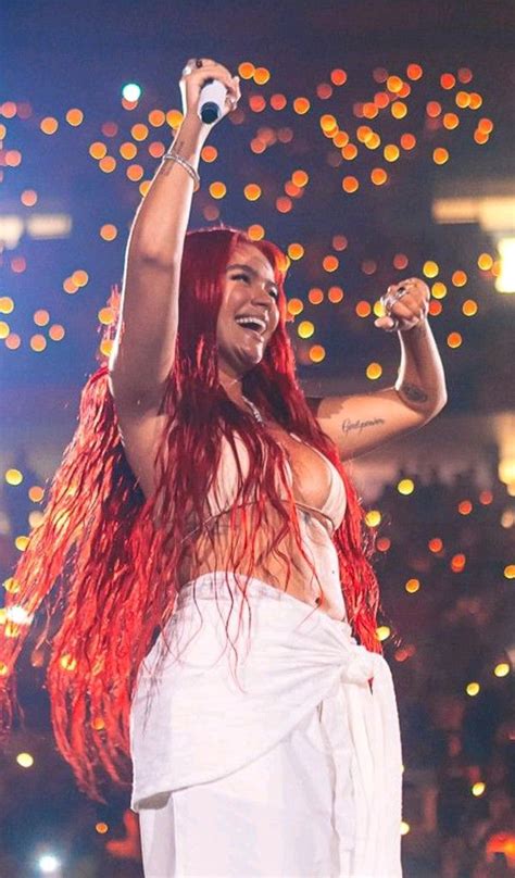 a woman with long red hair is on stage and has her arms in the air