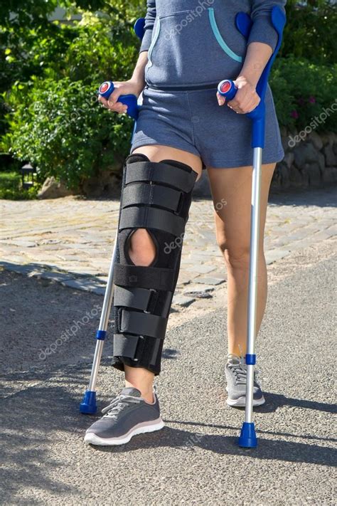 Woman Wearing A Leg Brace Walking On Crutches Stock Photo By