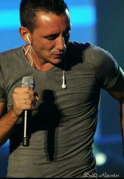 A Man Holding A Microphone In His Right Hand And Listening To Music On