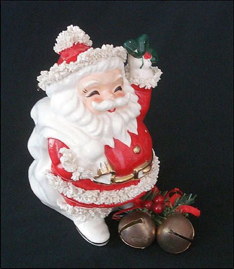 A Santa Clause Figurine Sitting Next To Two Bells