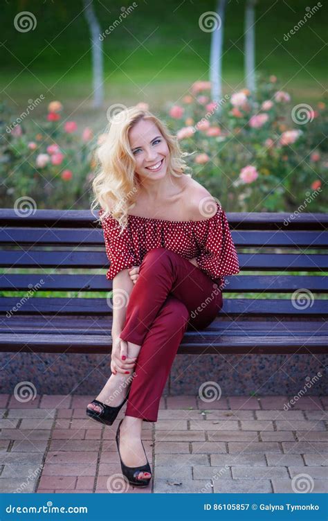 Beautiful Blonde Woman Sitting On A Bench In The Park Stock Image