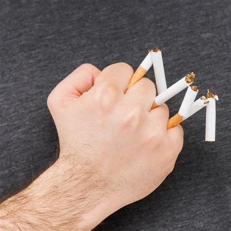 Close up de um mão homem segurando cigarro quebrado em seu