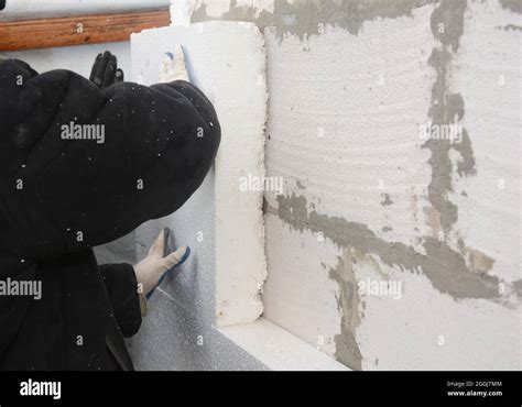 Builder Installing Rigid Styrofoam Insulation Board For Energy Saving