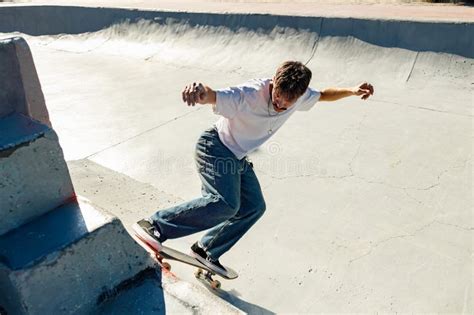 Full Body Of Young Male Skater In Casual Outfit Doing Trick On