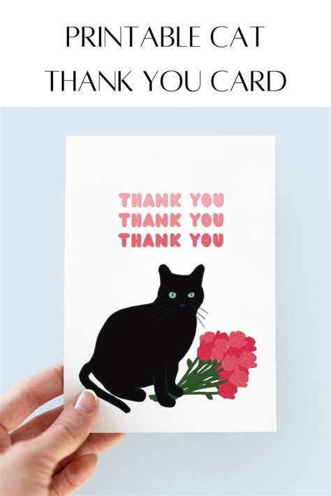 a hand holding up a thank card with a black cat and red flowers on it