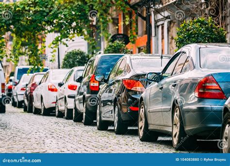 Many Cars Parked On Street In City In Sunny Summer Day Row Of City