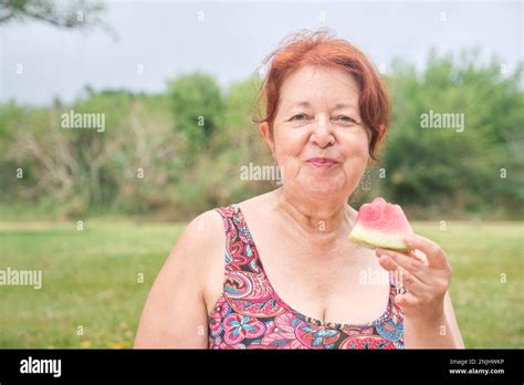 Portrait Of A Mature Latin Woman Looking At Camera While Enjoying A Slice Of Watermelon Outdoors