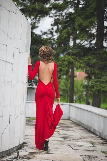 Vista Trasera De Una Mujer Rizada Rubia Sexy Con Un Vestido Rojo Sin