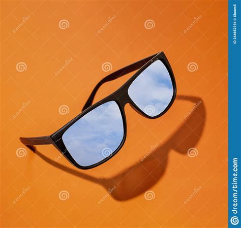 Black Sunglasses With A Reflection Of The Blue Sky With Clouds On A