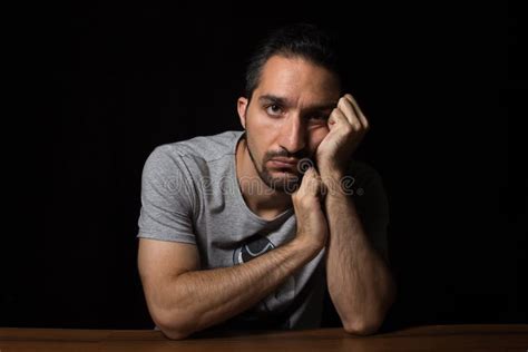 Un Hombre Con Una Cara Aburrida Sentado En Una Mesa Foto De Archivo