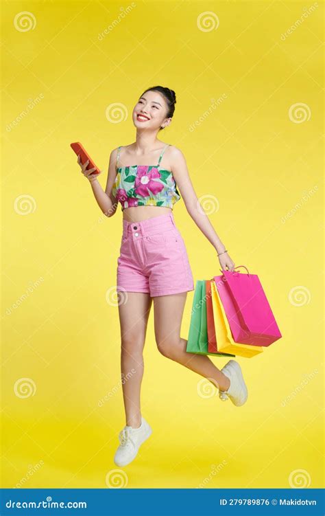 Full Length Of Happy Young Attractive Shopaholic Woman Raising Shopping Bags And Holding Mobile