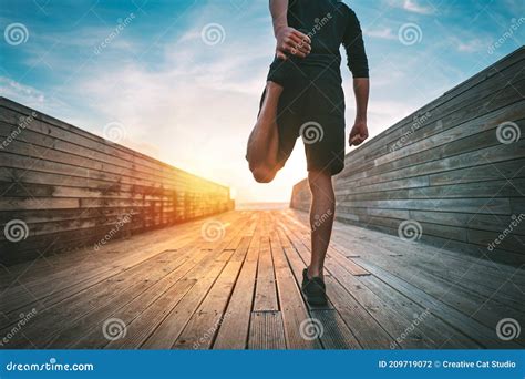 Man Warming And Stretching Legs Before Run Outdoors At Sunset Or