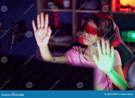 Adorable Hispanic Girl Streamer Playing Video Game Using Virtual Reality Glasses At Gaming Room