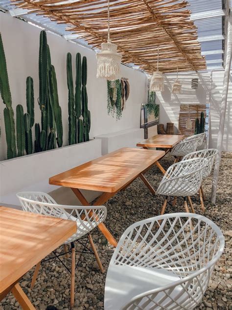 An Outdoor Dining Area With Wooden Tables And White Wicker Chairs